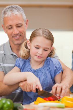 Portrait of a father showing his daughter how to cook clipart