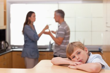 Sad little boy hearing his parents arguing clipart