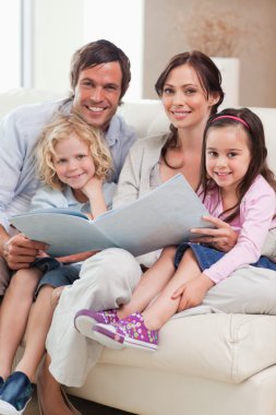 Portrait of a family looking at a photo album clipart