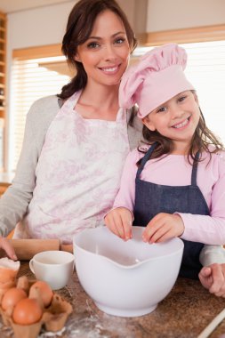 Portrait of a mother baking with her daughter clipart