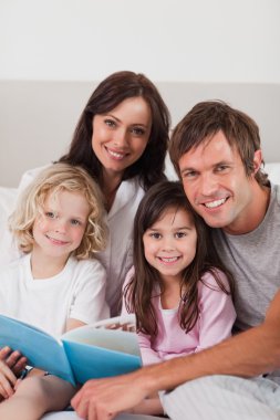 Portrait of a happy family reading a book clipart