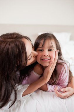 Portrait of a mother kissing her daughter clipart