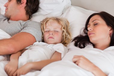 Boy sleeping between his parents clipart