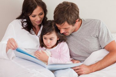 Parents reading a story to their daughter clipart