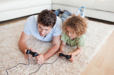 Focused boy and his father playing video games clipart