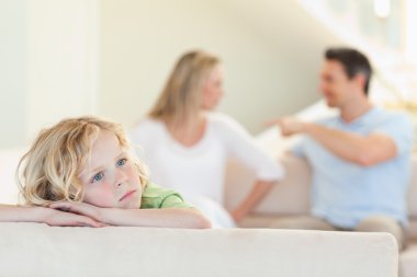 Sad boy with fighting parents behind him clipart