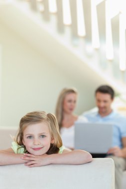 Smiling little girl with parents behind her clipart