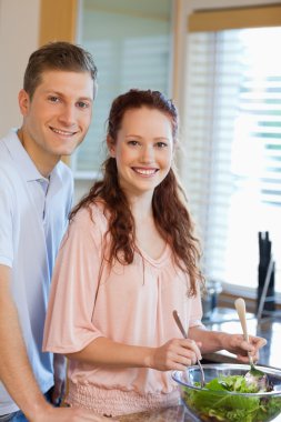 Couple with green salad in the kitchen clipart