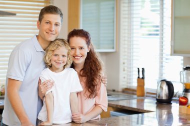 Smiling family standing behind the kitchen counter clipart