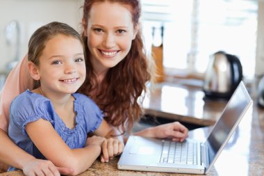 Mother and daughter with notebook in the kitchen clipart