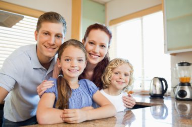 Family standing together behind the kitchen counter clipart