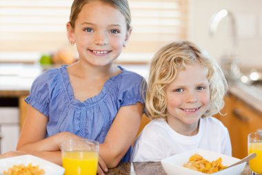 Brother and sister with breakfast in the kitchen clipart