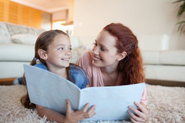 Mother and daughter with periodical on the floor clipart