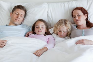 Adorable family sleeping in the bed together clipart