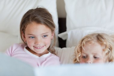 Girl reading a fairy tale for her brother clipart