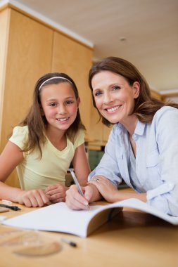 Mother helping daughter with homework clipart