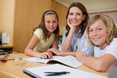 Mother doing homework with children clipart