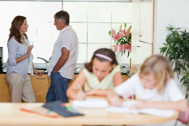 Parents talking with children doing homework in front of them clipart