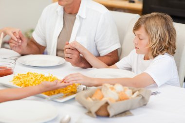 Family saying a prayer before dinner clipart