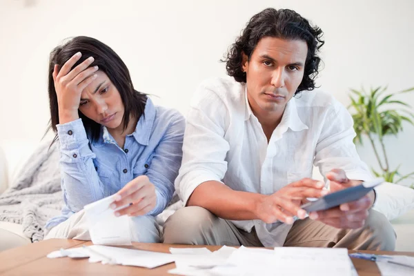 Frustrated couple checking their bills in the living room — Stock Photo, Image