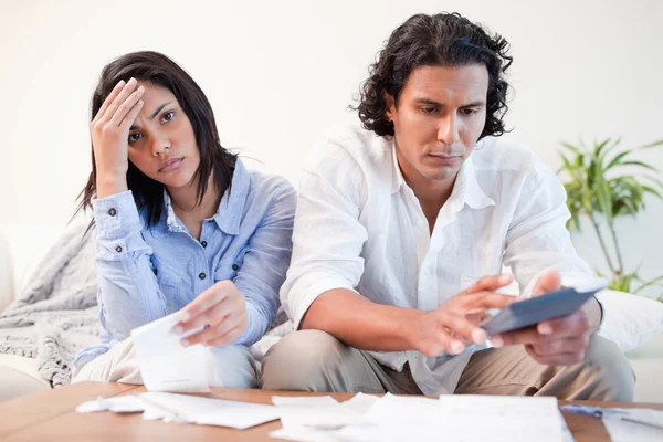 Frustrerad par gör sina beräkningar i vardagsrummet — Stockfoto