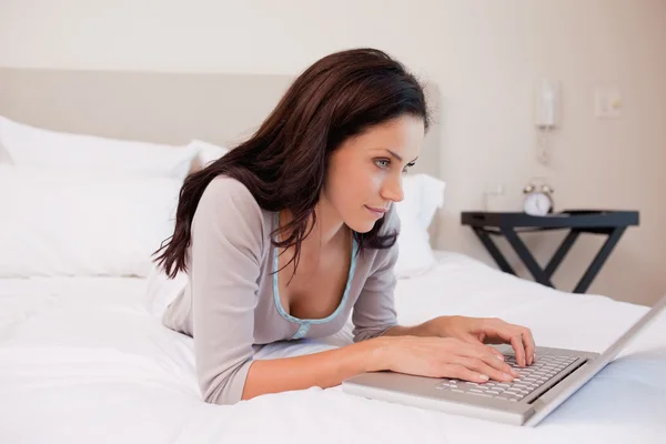 Frau liegt auf dem Bett und surft im Internet — Stockfoto