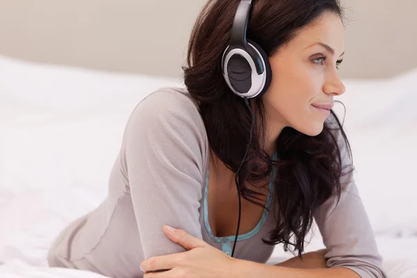 Woman with headphones on her bed — Stock Photo, Image