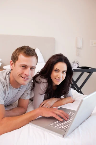 Lächelndes Paar mit Laptop im Schlafzimmer — Stockfoto