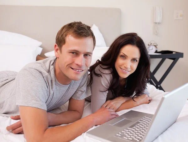 Happy couple using laptop on the bed together — Stock Photo, Image