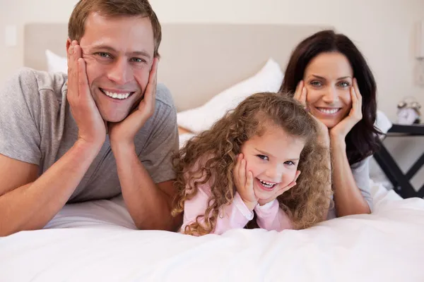 Famille souriante couchée sur le lit ensemble — Photo