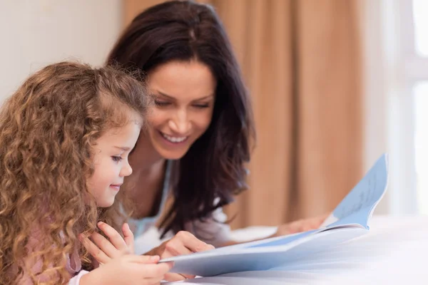 Side view of mother and daughter reading a book together — Stock Photo, Image