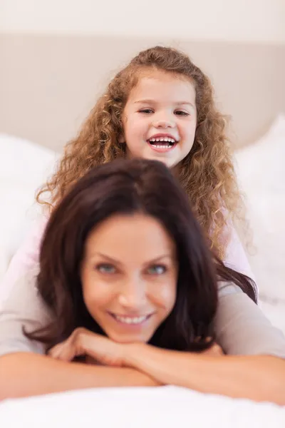 Girl sitting on her mothers back — Stock Photo, Image
