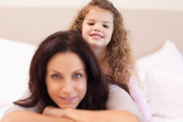 Smiling girl sitting on her mothers back — Stock Photo, Image