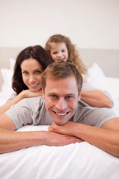 Cheerful family relaxing on the bed together — Stock Photo, Image