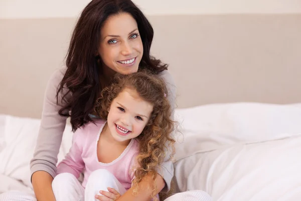 Mother hugging her daughter on the bed — Stock Photo, Image