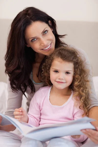 Uśmiechnięte matki czytając bajkę na dobranoc z jej małą córeczkę — Zdjęcie stockowe