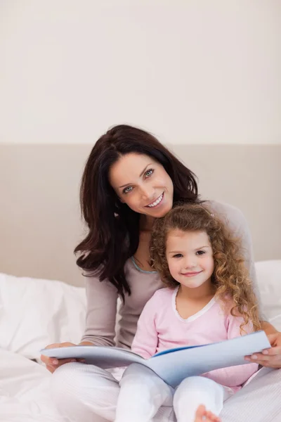 Мать и дочь читают книгу на кровати — стоковое фото