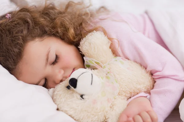 Chica abrazando su teddy mientras duerme — Foto de Stock