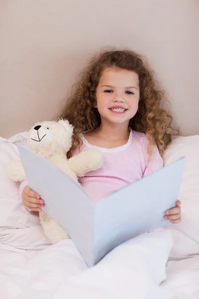 Девушка сидит на кровати с книгой — стоковое фото