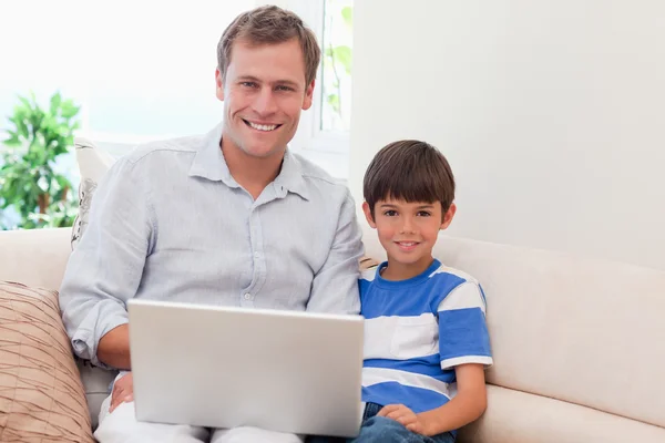父亲和儿子一起在沙发上的笔记本电脑 — 图库照片