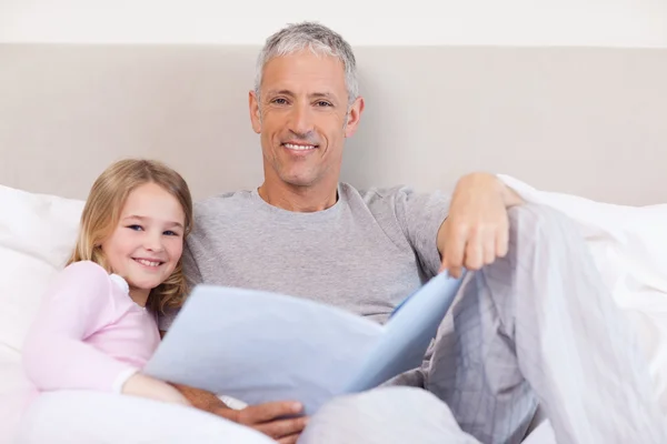 Lächelnder Vater liest seiner Tochter eine Geschichte vor — Stockfoto