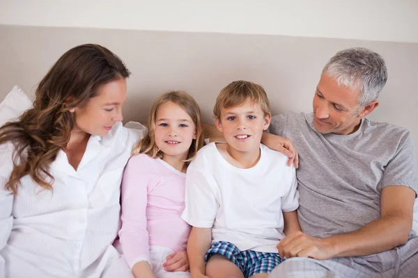 Smiling family lying on a bed — Stock Photo, Image