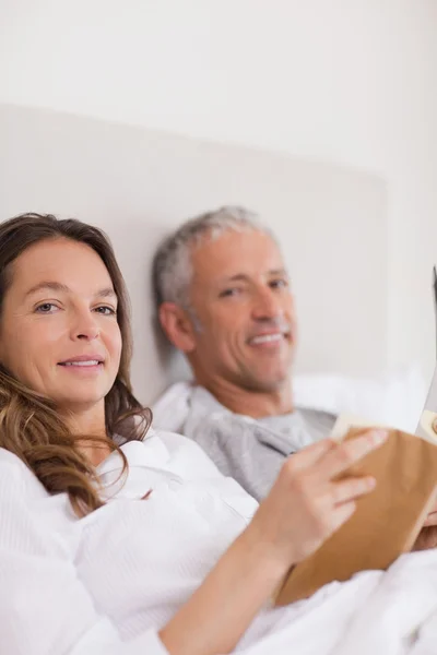Portrait of a woman reading a book while her husband is reading — Stock Photo, Image