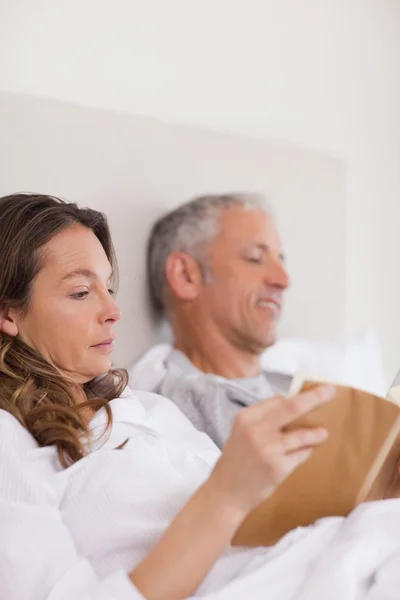 Portrait of a woman reading a book while her husband is reading — Stock Photo, Image