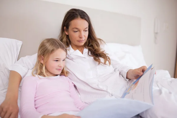 Mädchen liest mit ihrer Mutter ein Buch — Stockfoto