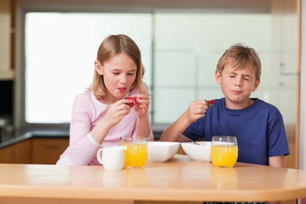 Siblings eating strawberries for breakfast — Stock Photo, Image