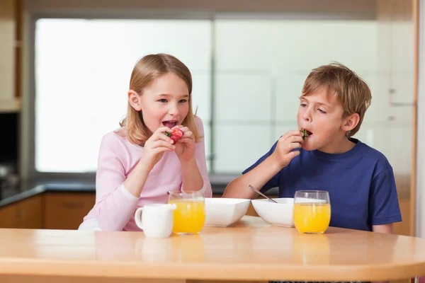 Children eating strawberries for breakfast — Stock Photo, Image