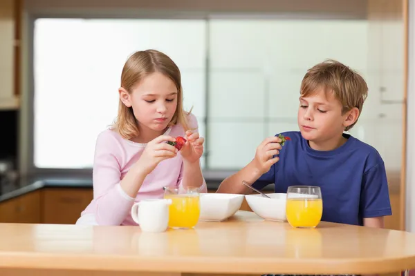 Cute children eating strawberries for breakfast — Stock Photo, Image