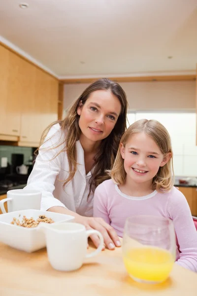 Porträtt av en glad mor och hennes dotter äter frukost — Stockfoto