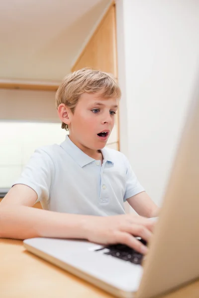 Portret van een verbaasd jongen met behulp van een laptop — Stockfoto